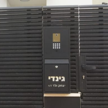 תיבת דואר שחורה בשילוב אינטרקום תלויה על חומה של בית פרטי