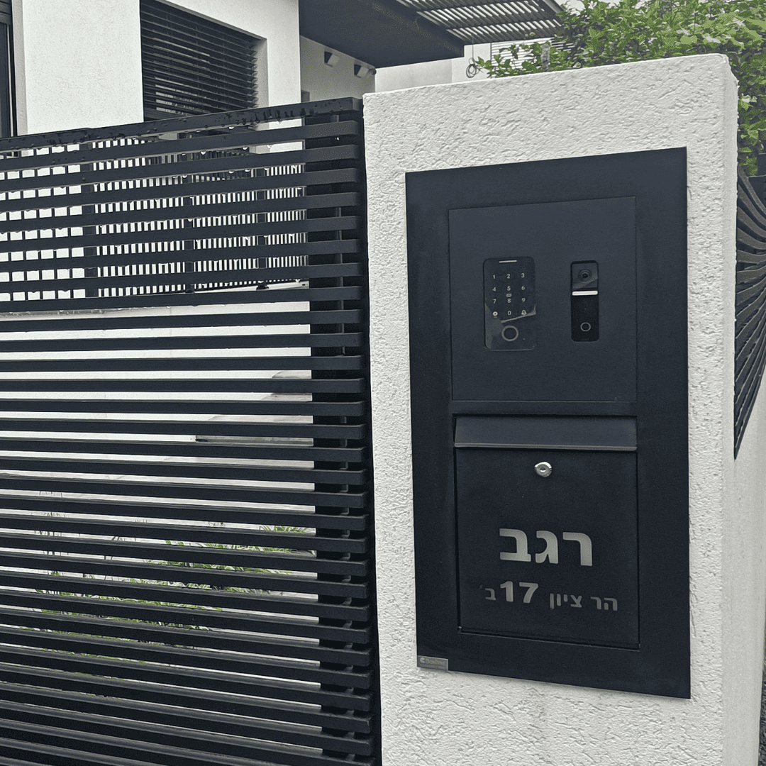 תיבת דואר שחורה מותקנת על חומת אבן בחזית בית פרטי