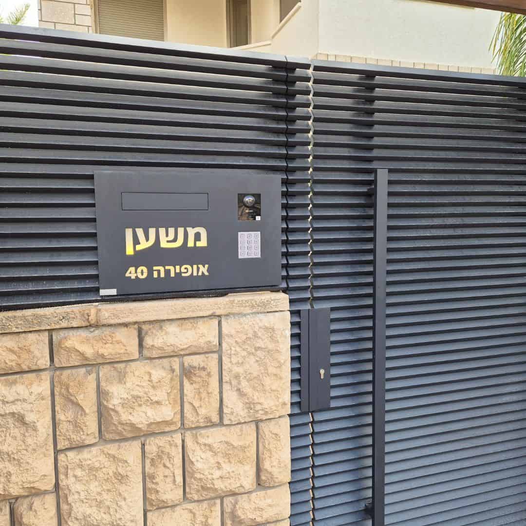 תיבת דואר מעוצבת מותקנת על גדר בחזית בית פרטי